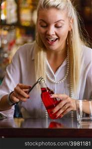 Woman working at the bar counter, holding red bottle lemonade. Woman working at the bar counter