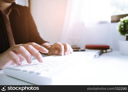 Woman working by using a laptop computer on wooden table. Hands typing on a keyboard.