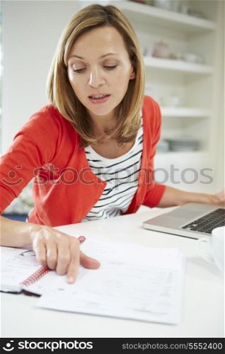 Woman Working From Home Using Laptop In Kitchen