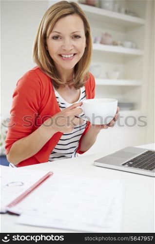 Woman Working From Home Using Laptop In Kitchen