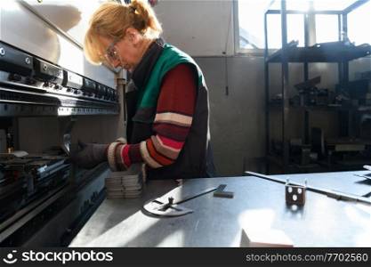 woman working in a modern factory and preparing material for a CNC machine. . High quality photo. woman working in a modern factory and preparing materia for a CNC machine. 