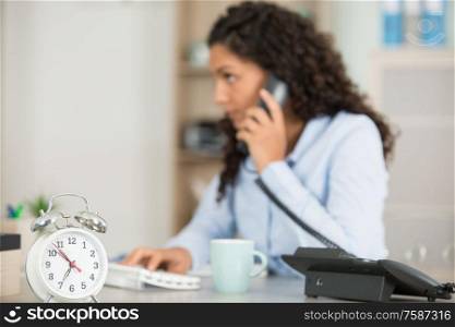 woman working in an office holding a clock