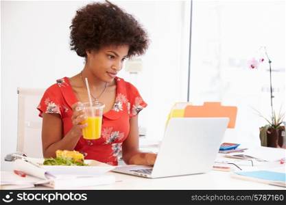 Woman Working In Design Studio Having Lunch At Desk