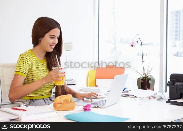 Woman Working In Design Studio Having Lunch At Desk