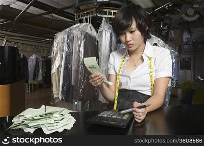 Woman working in the laundrette calculating receipts