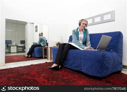 Woman working on a couch on her laptop, annexed to an office space