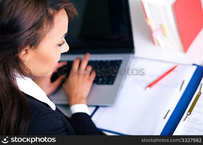 Woman working on a laptop, looking in a file