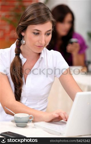 Woman working on her laptop in a cafe