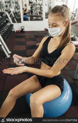 woman working out gym using hand sanitizer
