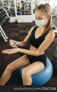 woman working out gym using hand sanitizer