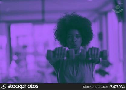 woman working out in a crossfit gym with dumbbells. happy healthy african american woman working out in a crossfit gym on weight loss with dumbbells duo tone filter