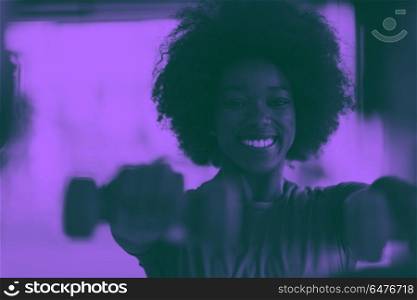 woman working out in a crossfit gym with dumbbells. happy healthy african american woman working out in a crossfit gym on weight loss with dumbbells duo tone filter