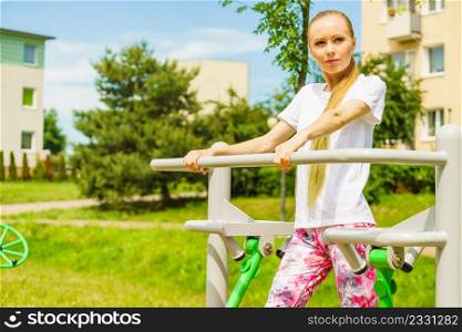 Woman working out in outdoor gym. Girl doing exercises on street public equipment.. Woman doing exercise in outdoor gym
