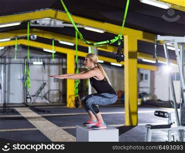 woman working out jumping on fit box. young athletic woman training jumping on fit box at crossfitness gym