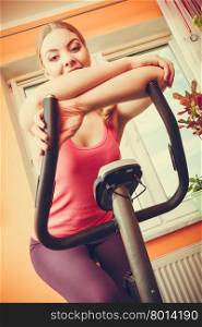 Woman working out on exercise bike. Fitness.. Active young woman working out on exercise bike stationary bicycle. Sporty girl training at home. Fitness and weight loss concept.