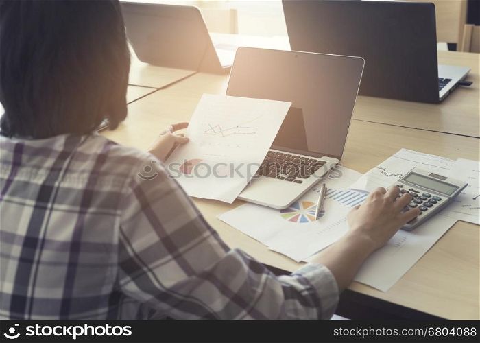 woman working with calculator, business document and laptop computer notebook, vintage tone