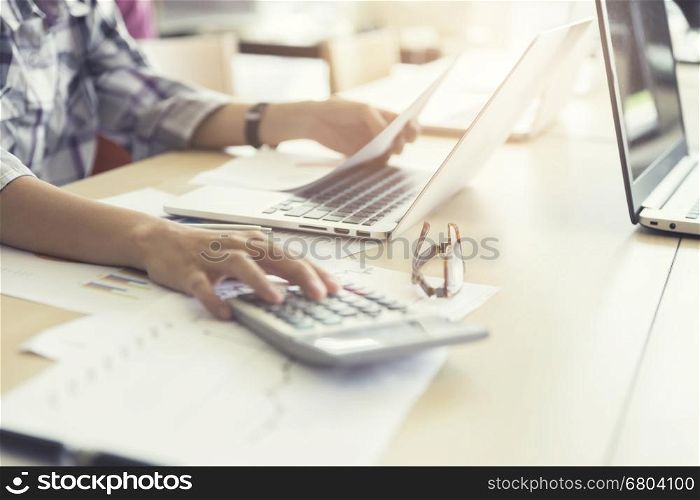 woman working with calculator, business document and laptop computer notebook, vintage tone
