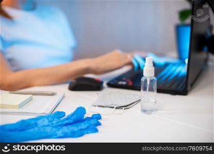 Woman working with notebook. Protective mask and Sanitizer spray on the working place. working from home