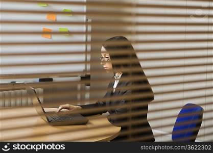 Woman workng in office view through blinds