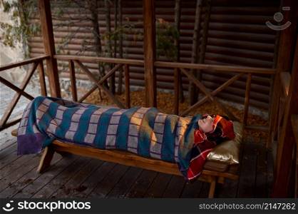 Woman wrapped in thermo blanket relaxing outdoor in wooden sauna backyard. Spa resort procedure. Woman wrapped in thermo blanket relaxing outdoor