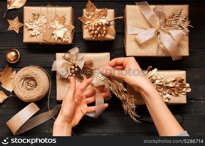 Woman wrapping christmas gifts. Creatively wrapped and decorated christmas presents in boxes on dark wooden background.Top view from above. Flat lay.