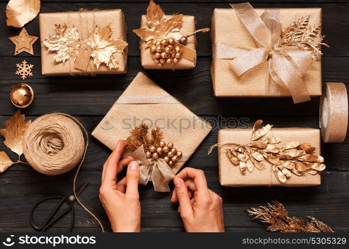 Woman wrapping christmas gifts. Creatively wrapped and decorated christmas presents in boxes on dark wooden background.Top view from above. Flat lay.