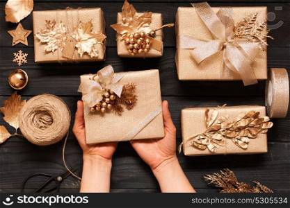 Woman wrapping christmas gifts. Creatively wrapped and decorated christmas presents in boxes on dark wooden background.Top view from above. Flat lay.