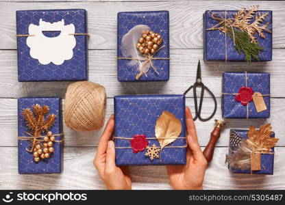 Woman wrapping christmas gifts. Creatively wrapped and decorated christmas presents in boxes on wooden background.Top view from above. Flat lay.