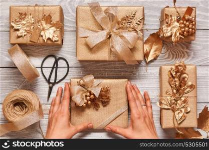 Woman wrapping christmas gifts. Creatively wrapped and decorated christmas presents in boxes on wooden background.Top view from above. Flat lay.