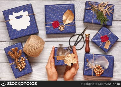 Woman wrapping christmas gifts. Creatively wrapped and decorated christmas presents in boxes on wooden background.Top view from above.