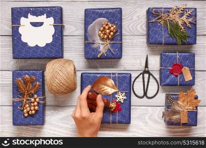 Woman wrapping christmas gifts. Creatively wrapped and decorated christmas presents in boxes on wooden background.Top view from above. Flat lay.