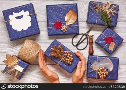 Woman wrapping christmas gifts. Creatively wrapped and decorated christmas presents in boxes on wooden background.Top view from above.