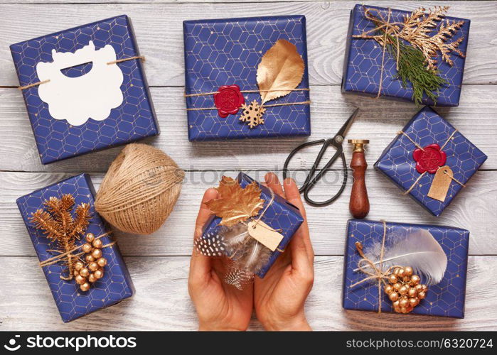 Woman wrapping christmas gifts. Creatively wrapped and decorated christmas presents in boxes on wooden background.Top view from above.