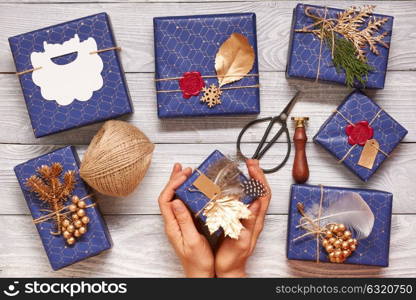 Woman wrapping christmas gifts. Creatively wrapped and decorated christmas presents in boxes on wooden background.Top view from above.