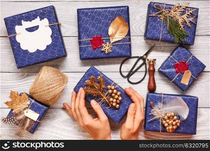 Woman wrapping christmas gifts. Creatively wrapped and decorated christmas presents in boxes on wooden background.Top view from above.