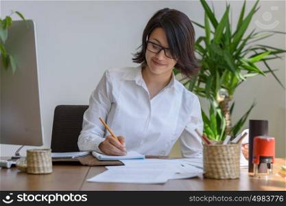 Woman writing at office during working day