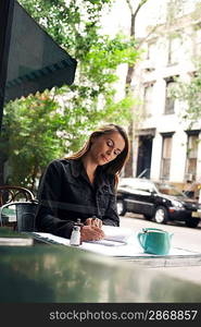 Woman Writing at Sidewalk Cafe