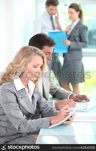 Woman writing in a notepad in an office environment
