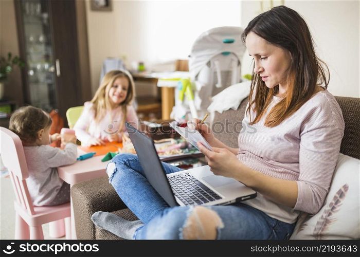 woman writing notes while using laptop