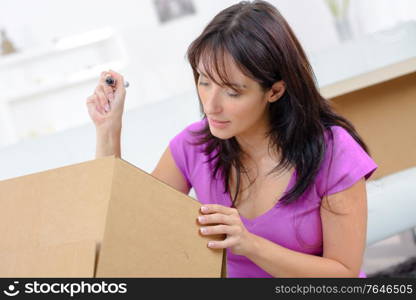 woman writing on cardboard box at table