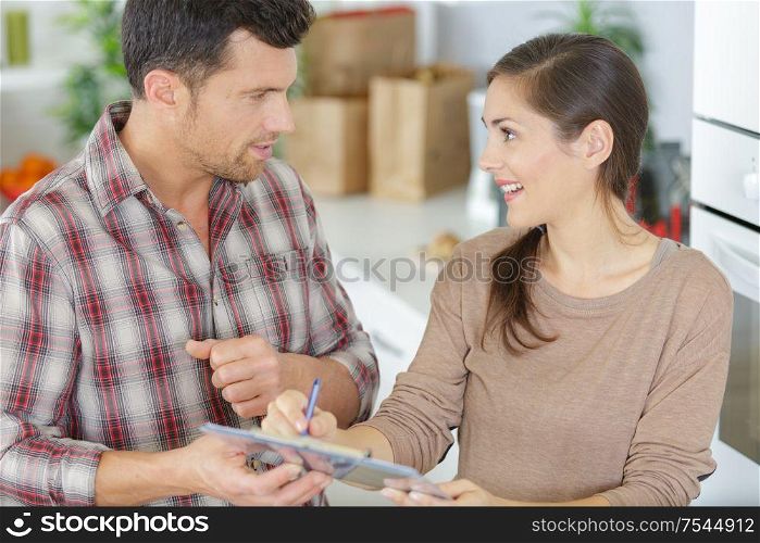 woman writing on clipboard in front of plumber
