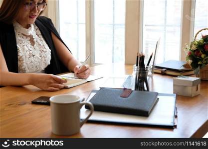 woman writing reminder schedule note on notebook. businesswoman working organizing plan at workplace coworking office