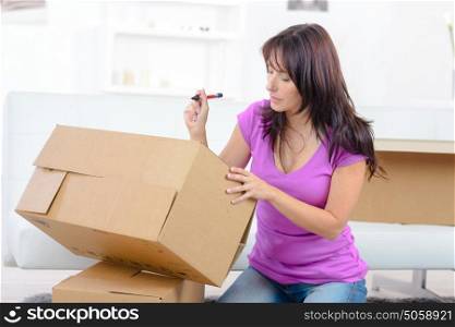 woman writing with pen on shipping box