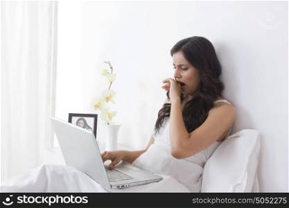 Woman yawning while working on laptop