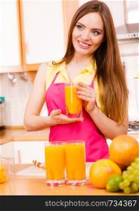 Woman young housewife in kitchen at home drinking fresh homemade orange juice drink. Healthy eating, vegetarian food, weight loss and people concept.. Woman in kitchen drinking fresh orange juice