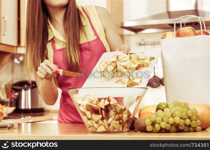 Woman young housewife in kitchen at home preparing fresh salad slicing apple fruits on cutting board. Healthy eating, cooking, vegetarian food, dieting and people concept. Woman housewife in kitchen cutting apple fruits