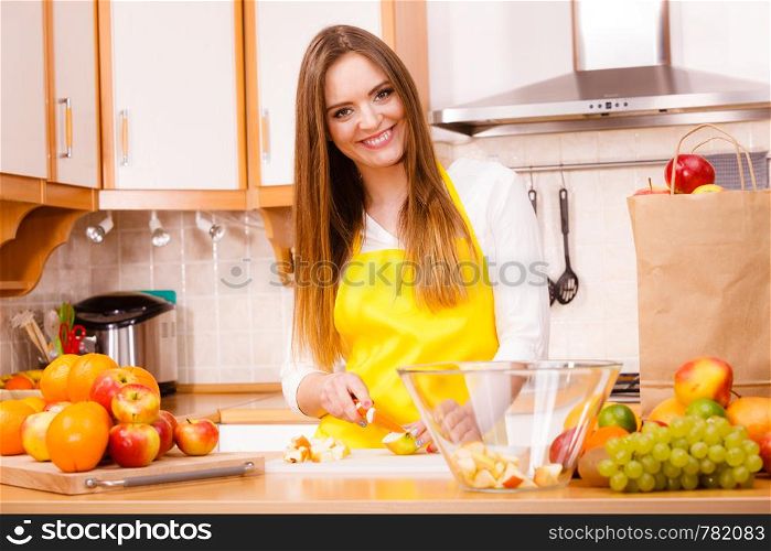 Woman young housewife in kitchen at home preparing fresh salad slicing apple fruits on cutting board. Healthy eating, cooking, vegetarian food, dieting and people concept. Woman housewife in kitchen cutting apple fruits
