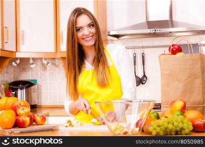 Woman young housewife in kitchen at home preparing fresh salad slicing apple fruits on cutting board. Healthy eating, cooking, vegetarian food, dieting and people concept