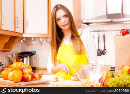 Woman young housewife in kitchen at home preparing fresh salad slicing apple fruits on cutting board. Healthy eating, cooking, vegetarian food, dieting and people concept