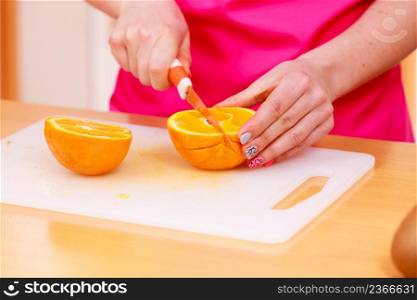 Woman young housewife in kitchen at home slicing fresh orange fruits on cutting board for salad or juicing. Healthy eating, cooking, raw food, dieting and people concept.. Woman housewife in kitchen cutting orange fruits